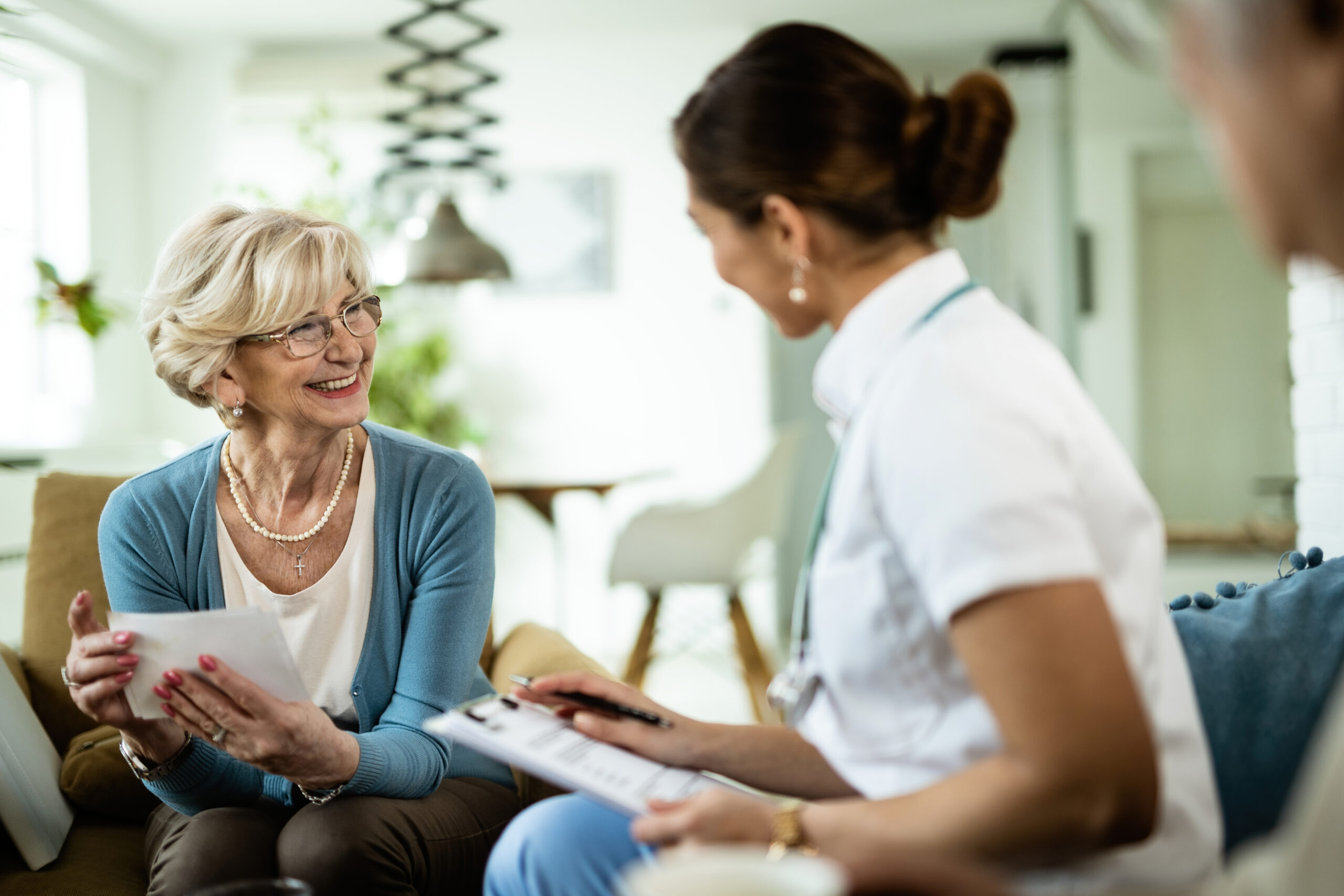 Ärztin im Gespräch mit einer älteren Patientin beim Hausbesuch